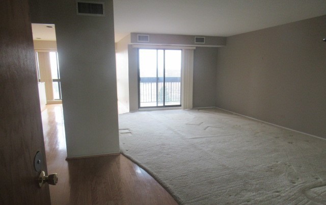 701 Forum Square, Unit 607 Glenview, IL 60025 - Photo 3 of 13 an empty room with wooden floor and windows