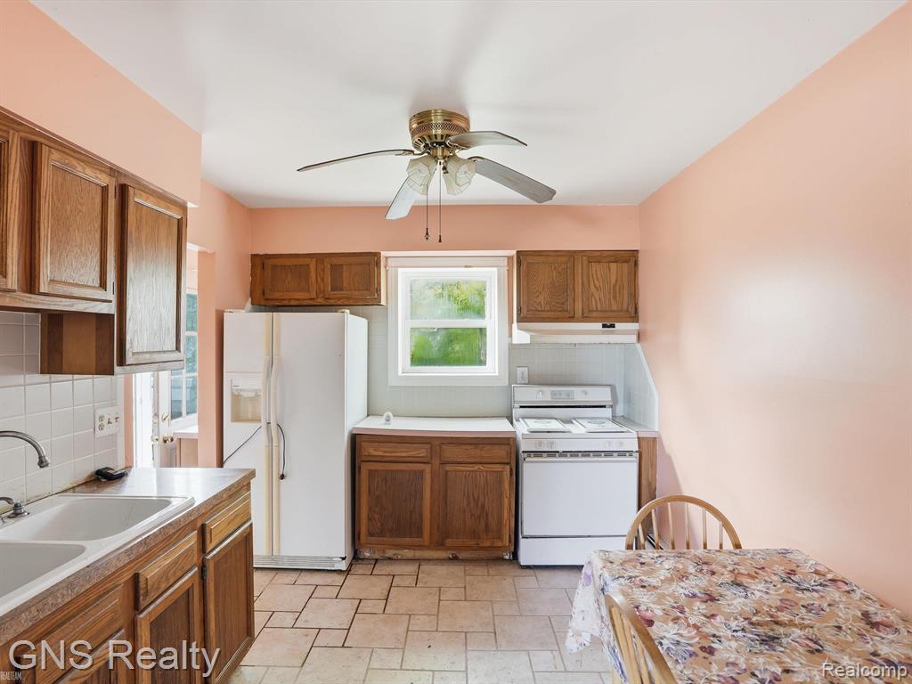 2717 Normandy Road Royal Oak, MI 48073 - Photo 10 of 13 Kitchen featuring wood cabinetry, a double basin sink, white tile backsplash, and a ceiling fan