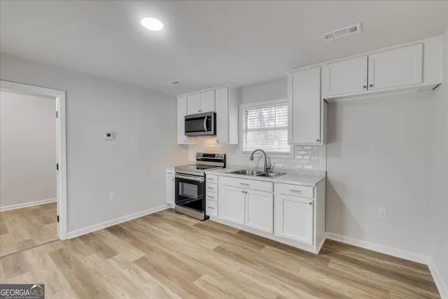 a kitchen with white cabinets and appliances