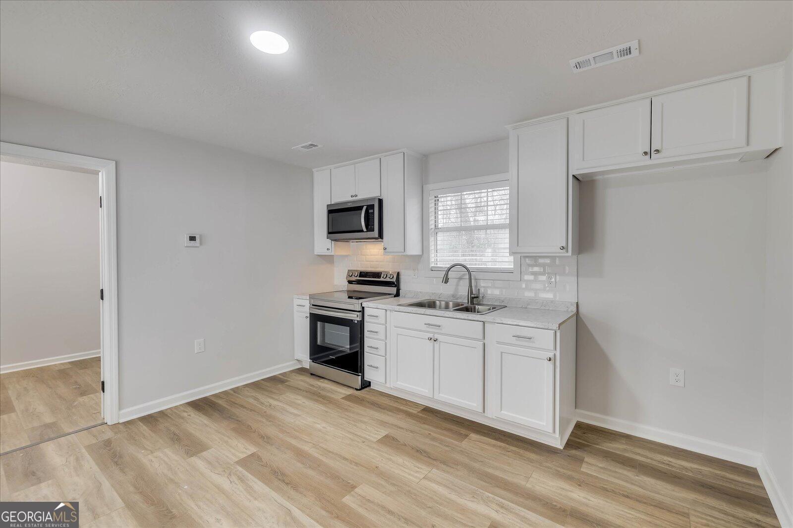4756 Mike Padgett Highway Augusta, GA 30906 - Photo 22 of 28 a kitchen with white cabinets and appliances