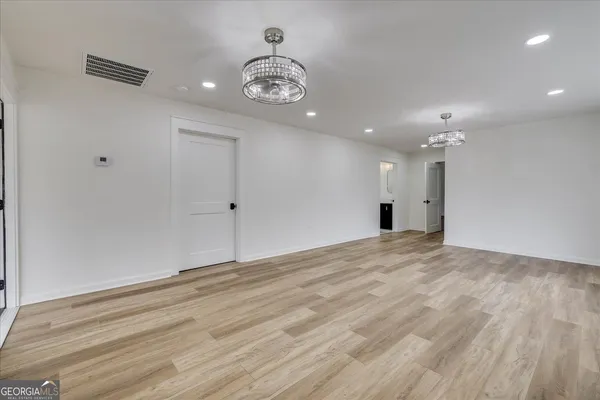 a view of an empty room with wooden floor and a ceiling fan