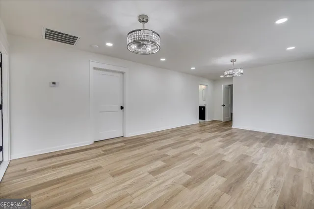 a view of an empty room with wooden floor and a ceiling fan