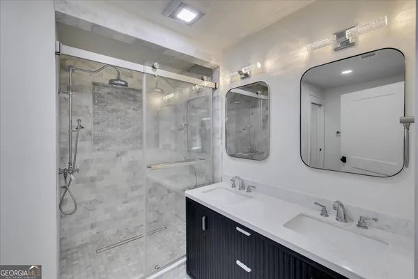 a bathroom with a double vanity sink mirror and shower