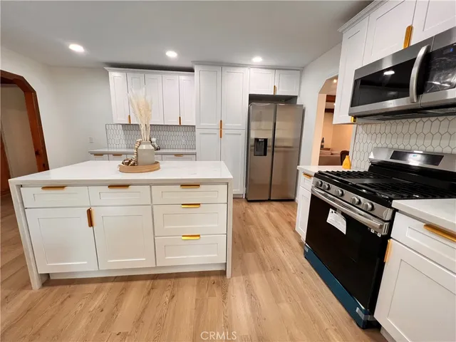 a kitchen with stainless steel appliances a stove a sink a refrigerator and cabinets