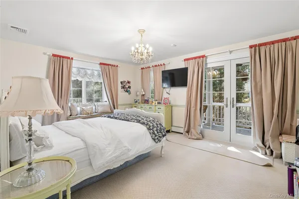 a bedroom with a bed flat screen tv and a large window
