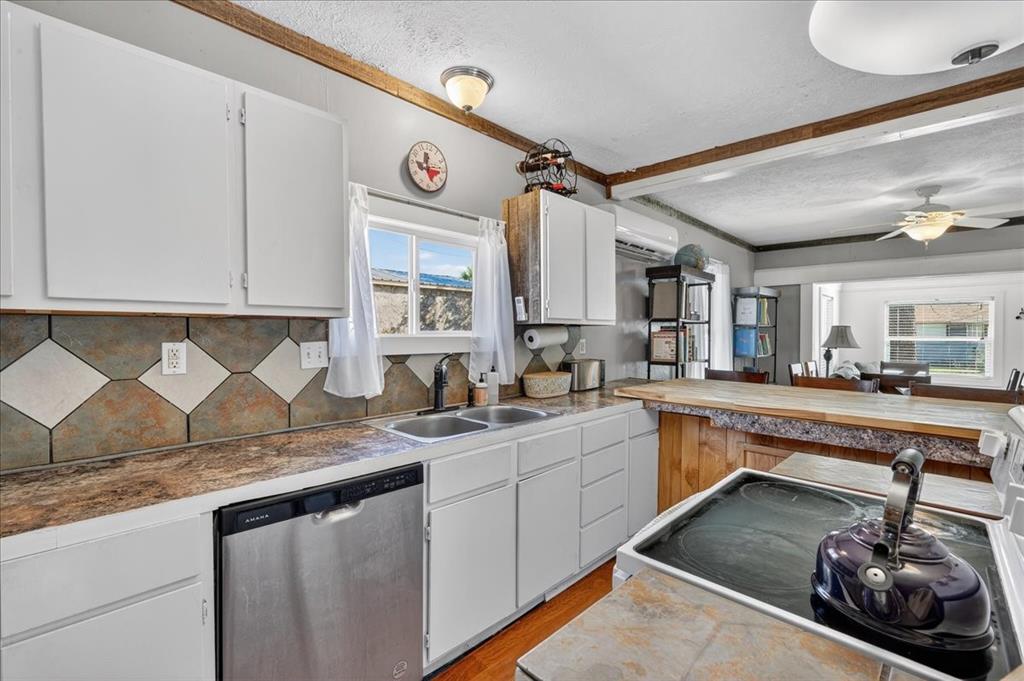 124 West Travis Dublin, TX 76446 - Photo 7 of 30 a kitchen with granite countertop a sink a stove and cabinets