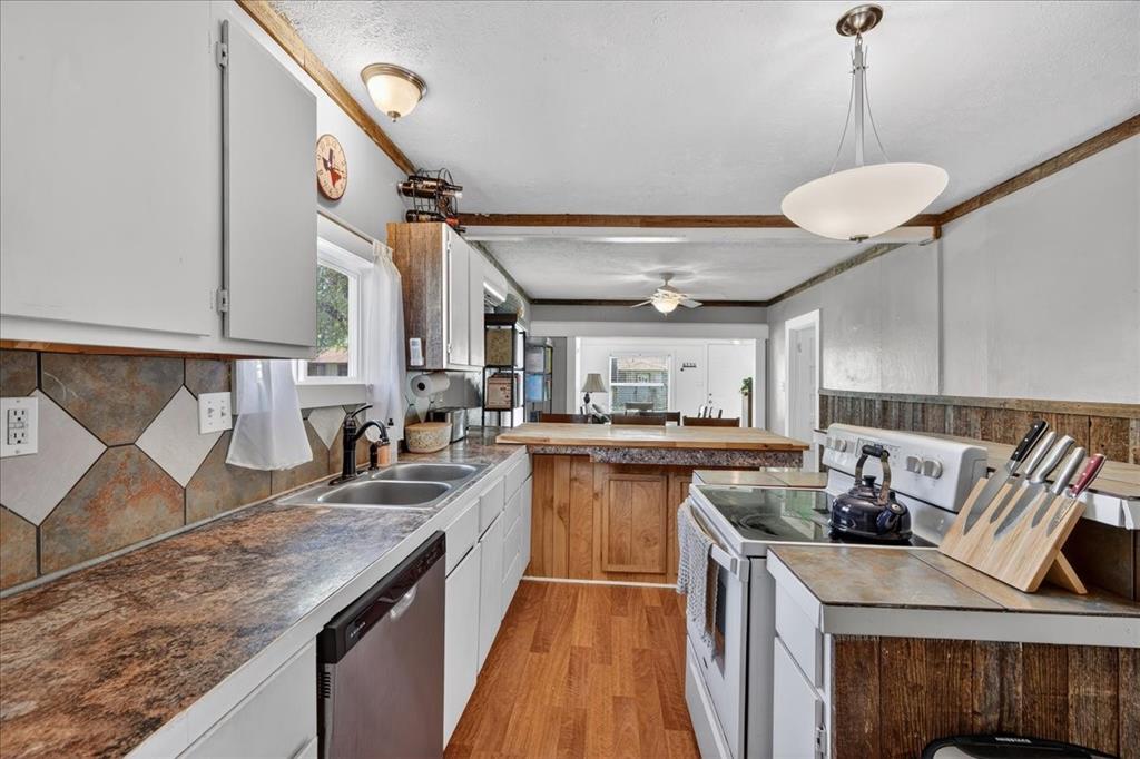 124 West Travis Dublin, TX 76446 - Photo 8 of 30 a kitchen with kitchen island granite countertop a sink a counter space appliances and cabinets