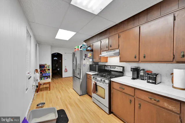 a kitchen with stainless steel appliances granite countertop a sink dishwasher stove and refrigerator with wooden floor