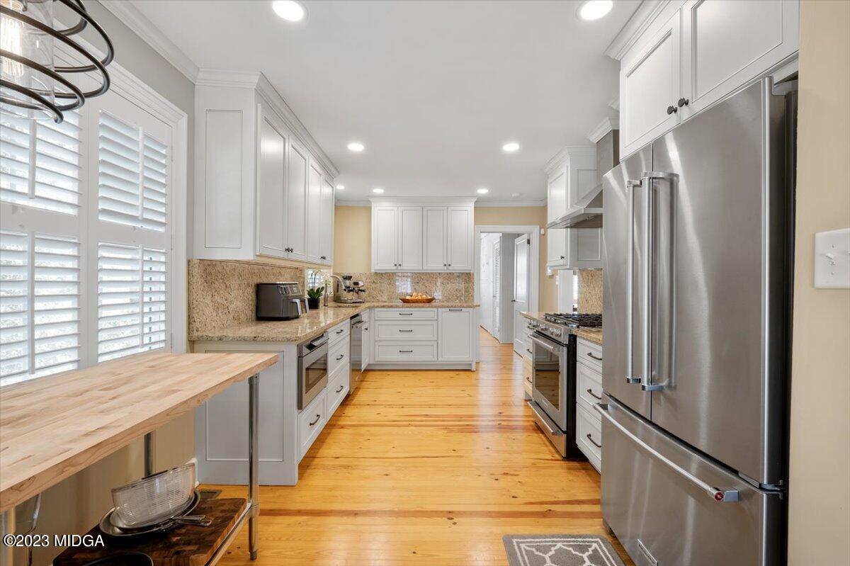 394 Overlook Road Macon, GA 31204 - Photo 7 of 29 a large kitchen with a refrigerator a sink dishwasher a stove and white cabinets with wooden floor