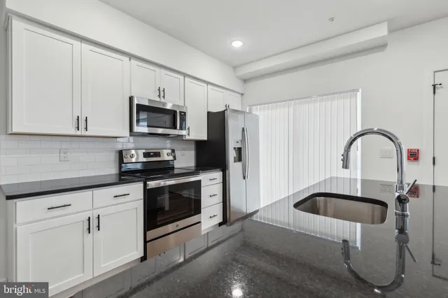 a kitchen with white cabinets and stainless steel appliances