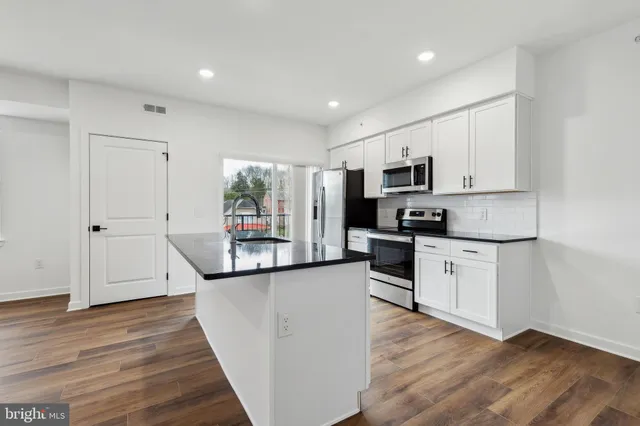 a kitchen with granite countertop a refrigerator stove top oven and sink
