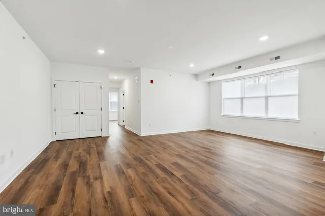 an empty room with wooden floor and windows