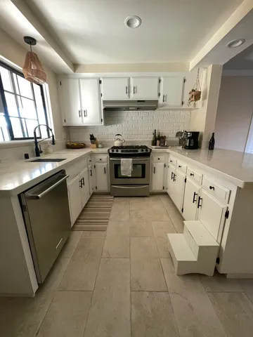 a kitchen with granite countertop a sink a stove and cabinets