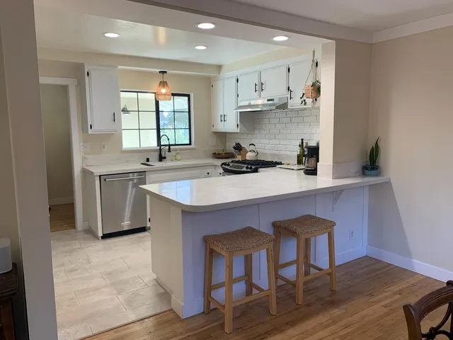 a kitchen with stainless steel appliances a sink a stove a refrigerator dining table and chairs