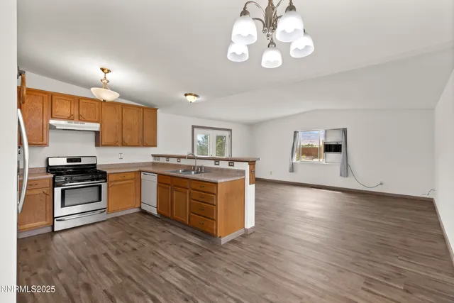 a kitchen with granite countertop a stove top oven a sink cabinets and wooden floor