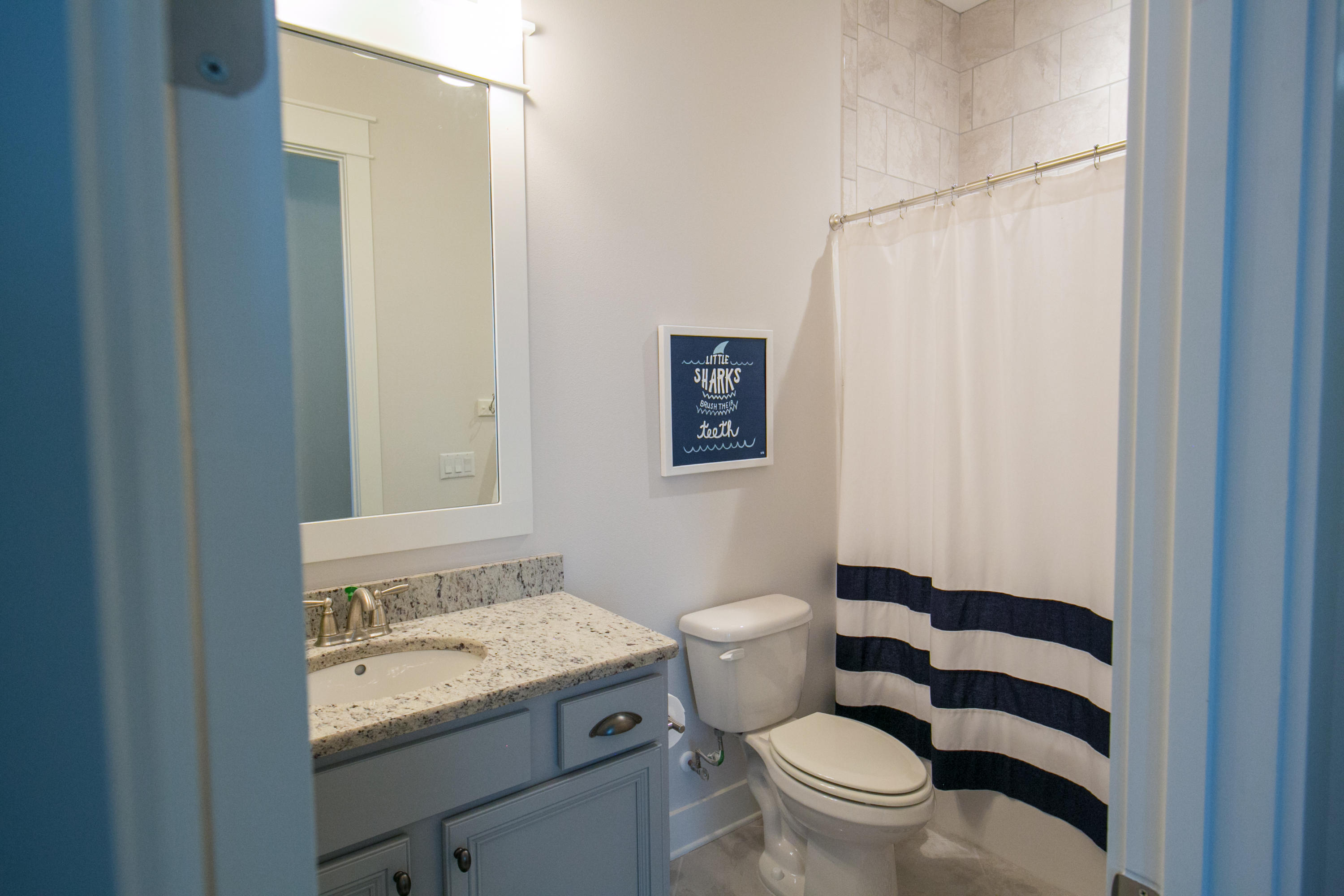 85 York Ln Inlet Beach, Unit B Inlet Beach, FL 32461 - Photo 10 of 31 a bathroom with a granite countertop toilet a sink and a mirror