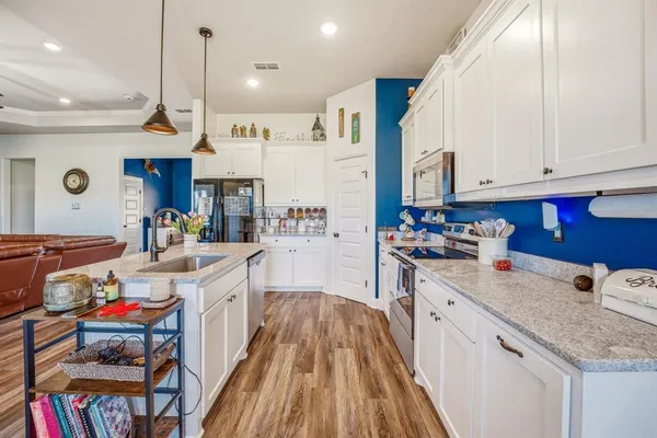 a kitchen that has a lot of cabinets in it and wooden floors