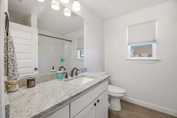 a bathroom with a granite countertop toilet sink and mirror
