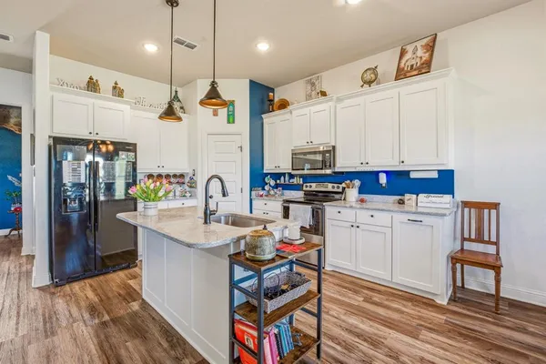 a kitchen that has a lot of cabinets a sink and a wooden floor