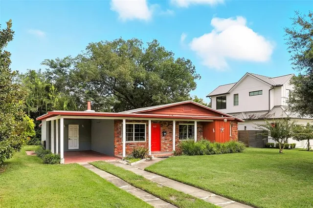 a view of a yard in front of a house with plants and large tree