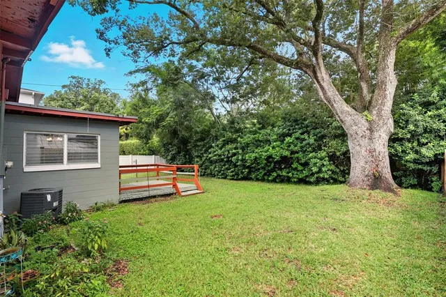 a backyard of a house with potted plants and large tree