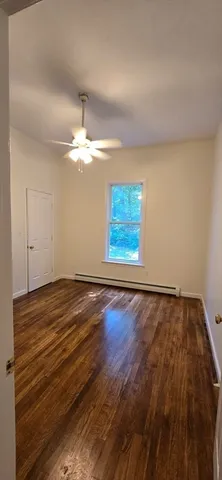 an empty room with wooden floor closet and windows