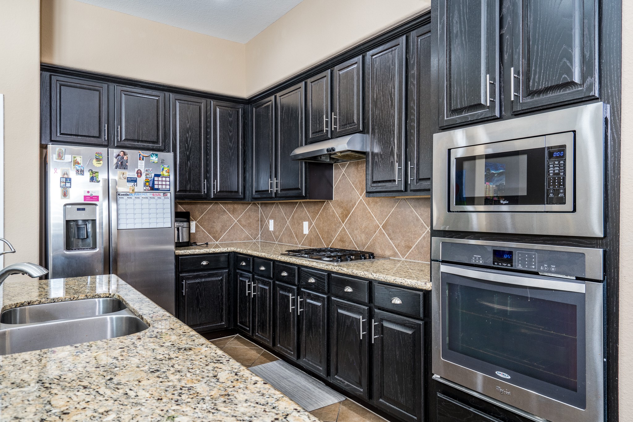 9115 Monarch Mist Lane Houston, TX 77070 - Photo 11 of 26 a kitchen with stainless steel appliances granite countertop wooden cabinets a stove top oven a sink and dishwasher