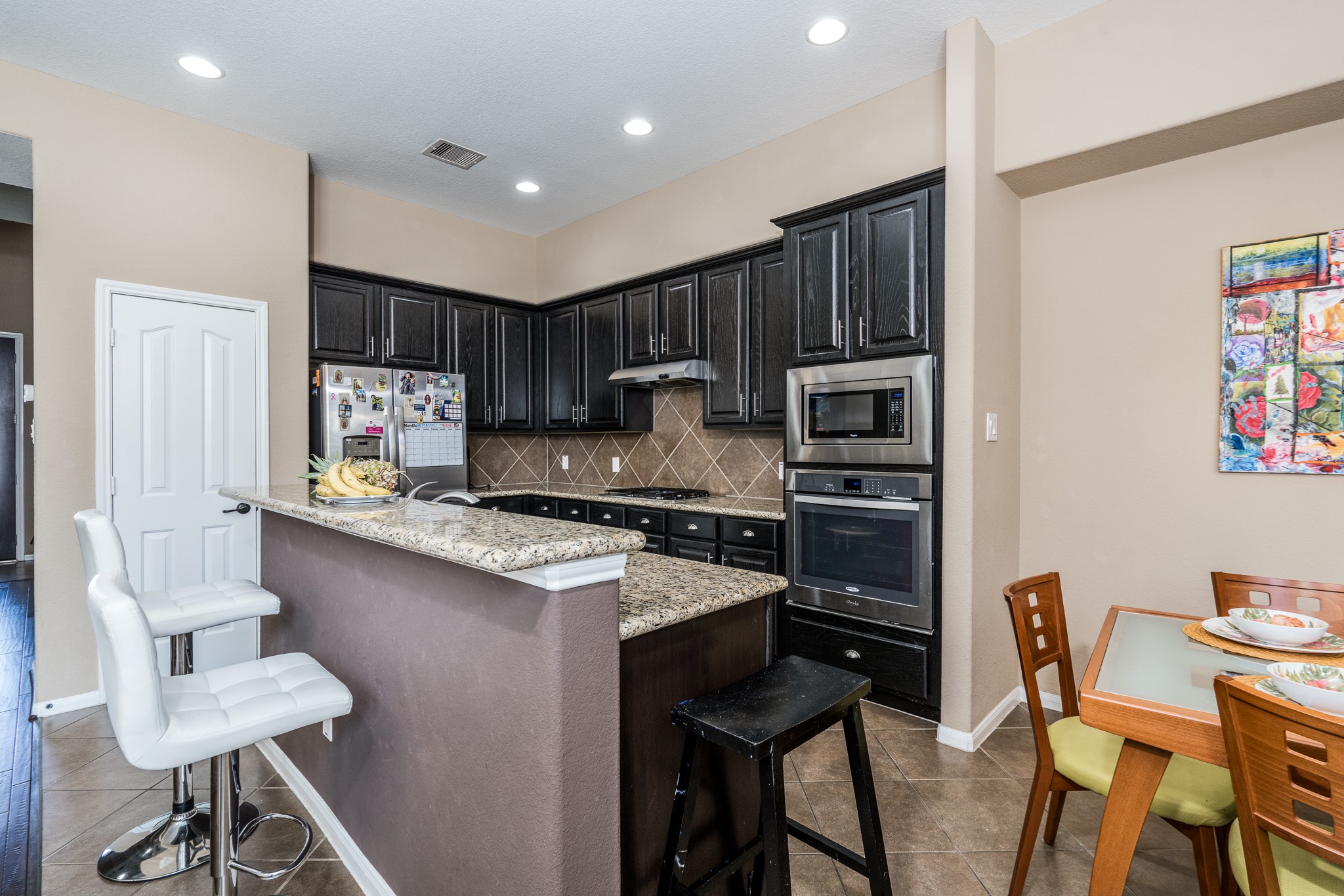 9115 Monarch Mist Lane Houston, TX 77070 - Photo 13 of 26 a kitchen with stainless steel appliances granite countertop a stove a sink a microwave a refrigerator and chairs