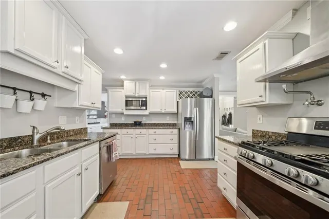a kitchen with stainless steel appliances granite countertop a stove refrigerator sink and cabinets