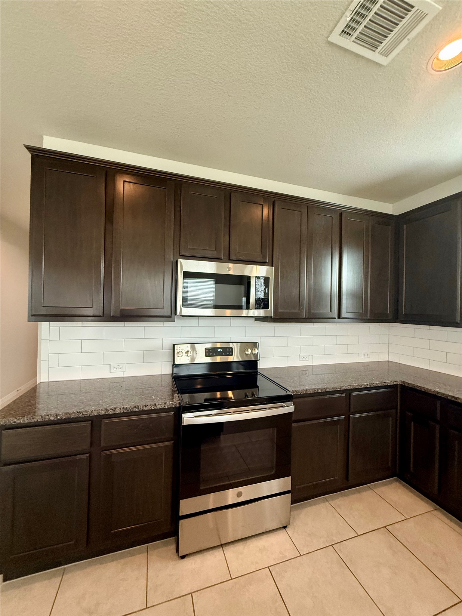 212 Lake Placid Run Elgin, TX 78621 - Photo 6 of 27 Culinary delights await with abundant dark cabinetry, rich granite counters, and a sleek stainless-steel range.