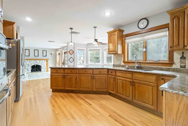 a kitchen with stainless steel appliances granite countertop a sink a stove and a wooden floors