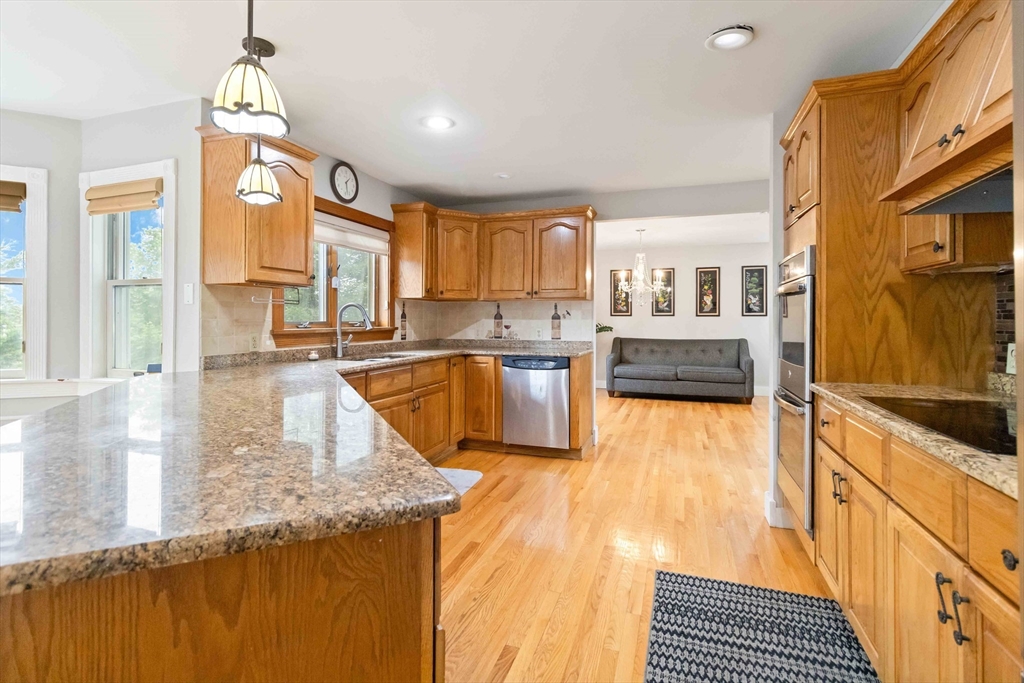 141 Gardiner Road Quincy, MA 02169 - Photo 9 of 39 a large kitchen with stainless steel appliances granite countertop a stove a sink dishwasher and cabinets with wooden floor