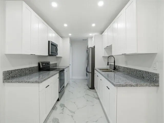 a kitchen with stainless steel appliances granite countertop a stove a sink and a microwave
