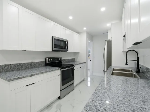 a kitchen with a refrigerator sink and cabinets