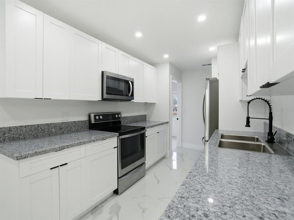 390 Hazel Circle Punta Gorda, FL 33982 - Photo 12 of 44 a kitchen with stainless steel appliances granite countertop a stove a sink and a microwave