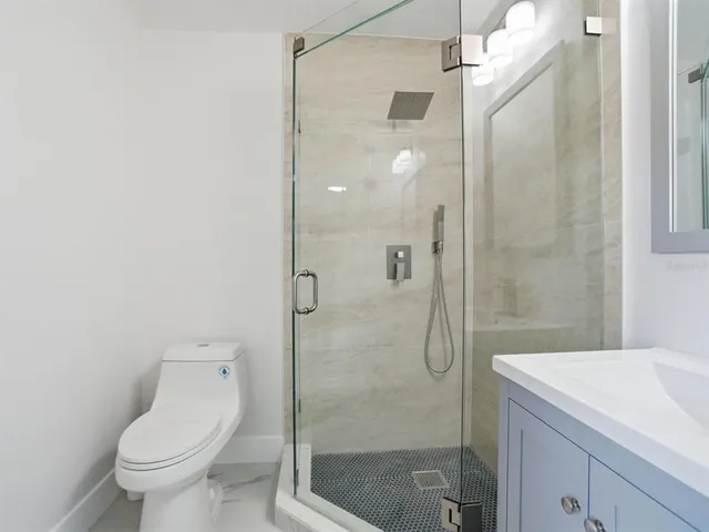 a bathroom with a shower sink vanity and toilet