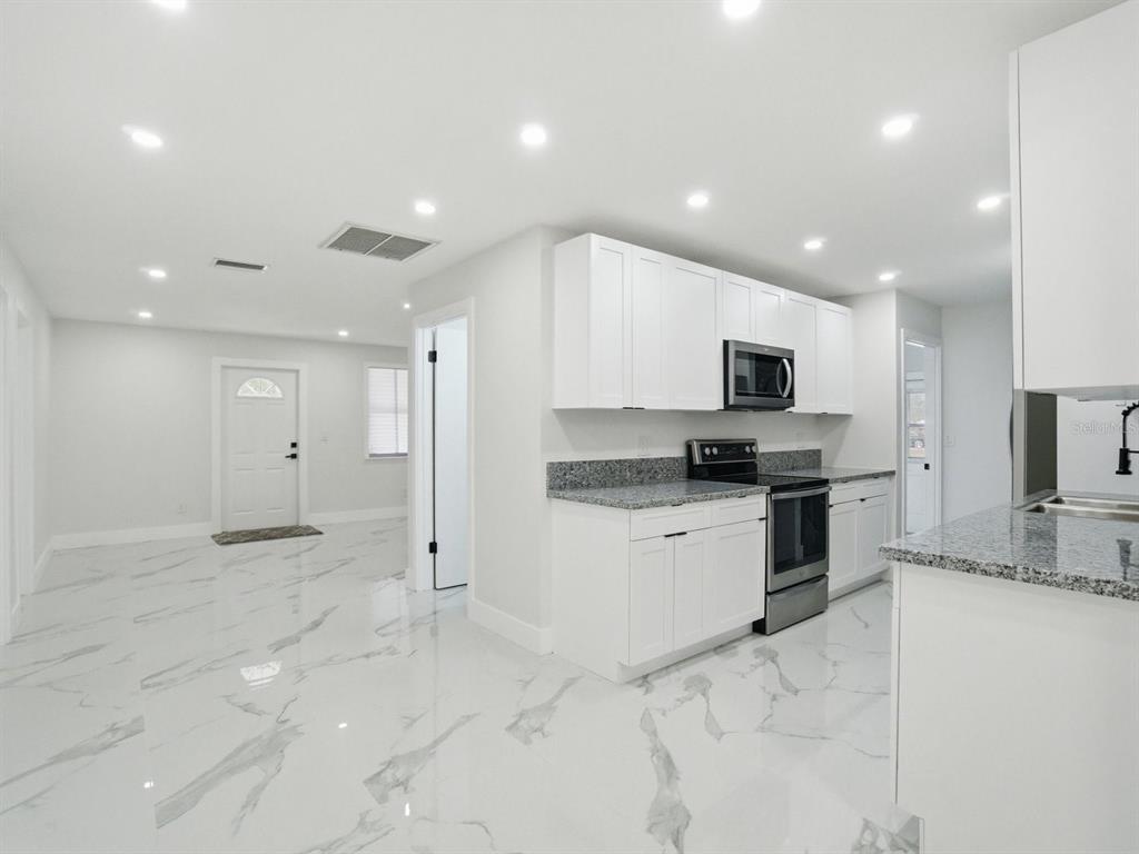 390 Hazel Circle Punta Gorda, FL 33982 - Photo 10 of 44 a large kitchen with stainless steel appliances kitchen island granite countertop a sink and cabinets