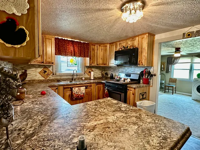 a kitchen with kitchen island granite countertop a stove a sink and a microwave