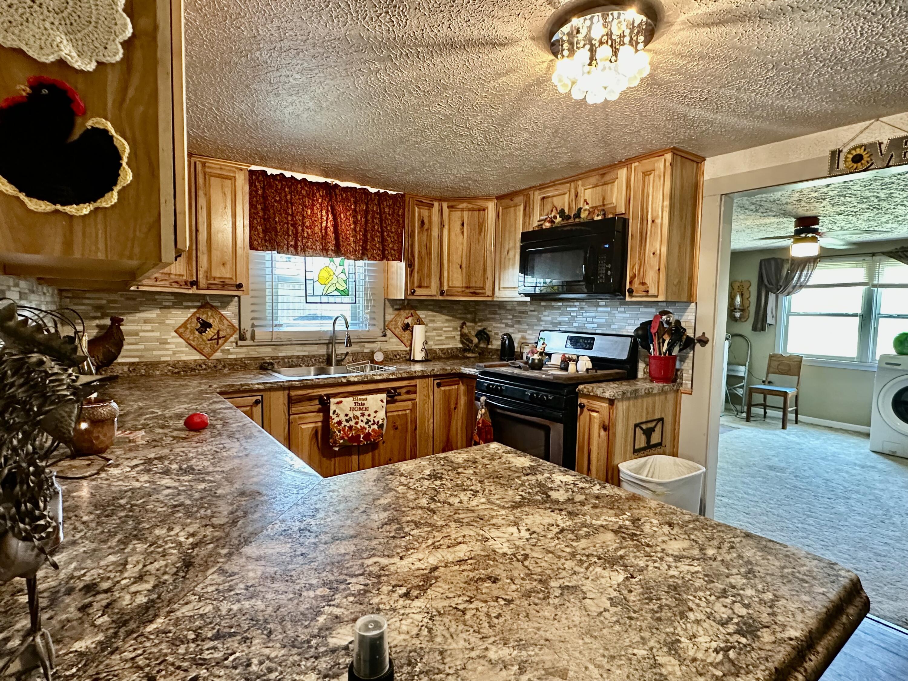 600 Mulberry Street Turkey, TX 79261 - Photo 14 of 29 a kitchen with kitchen island granite countertop a stove a sink and a microwave