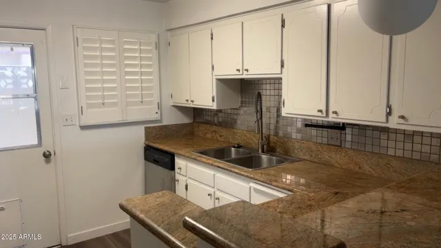 a kitchen with granite countertop a sink a stove and cabinets