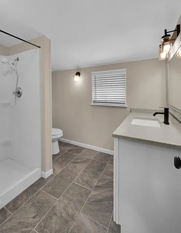 a bathroom with a sink a toilet and shower