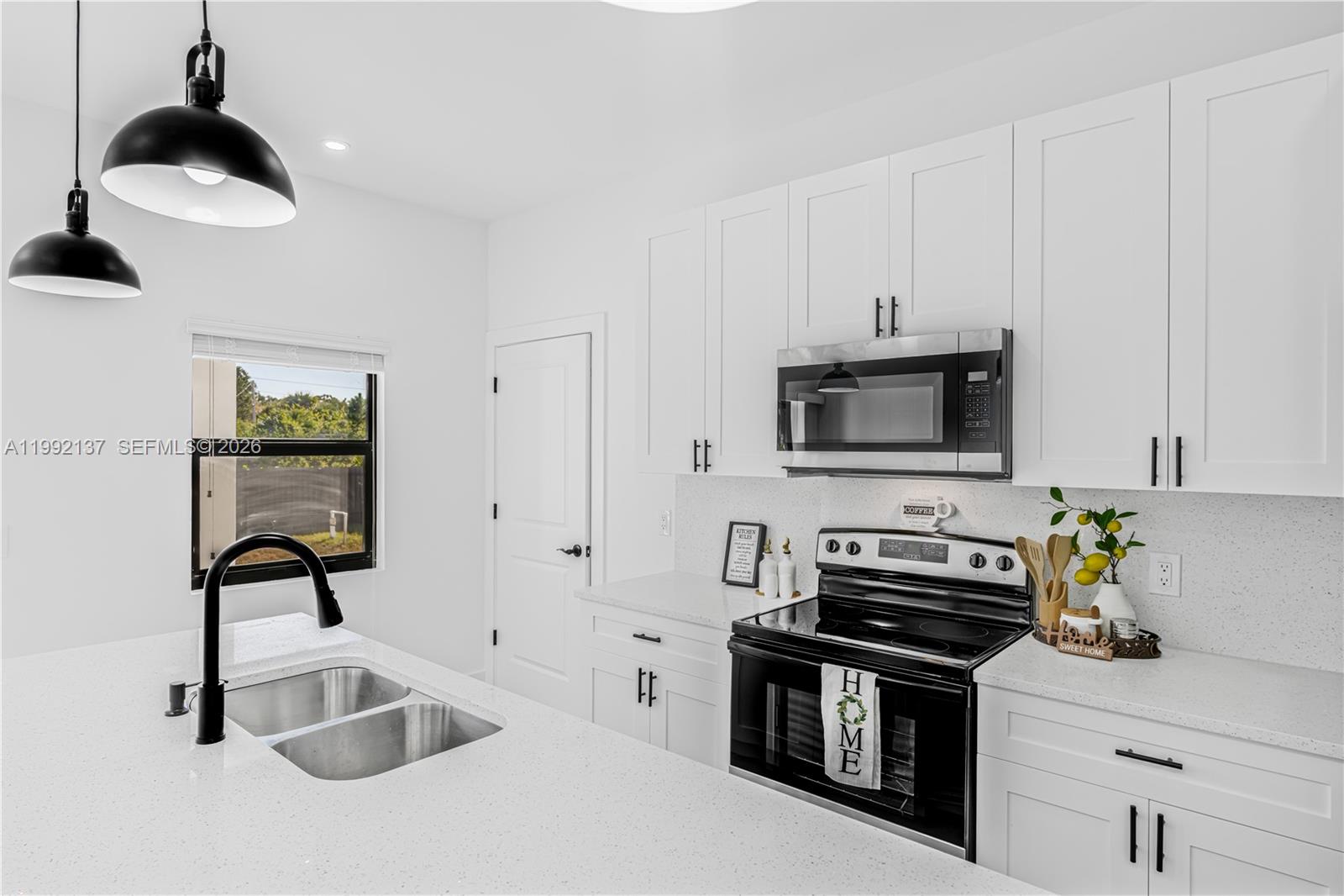 747 Roma Avenue South Lehigh Acres, FL 33974 - Photo 11 of 31 a kitchen with stainless steel appliances a sink a stove and a microwave
