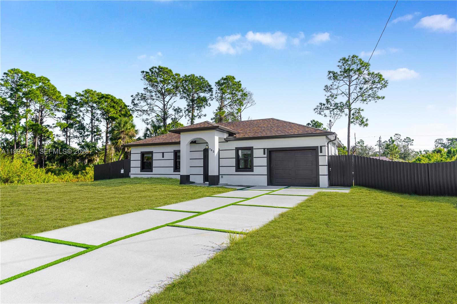 747 Roma Avenue South Lehigh Acres, FL 33974 - Photo 2 of 31 a front view of a house with a garden and trees
