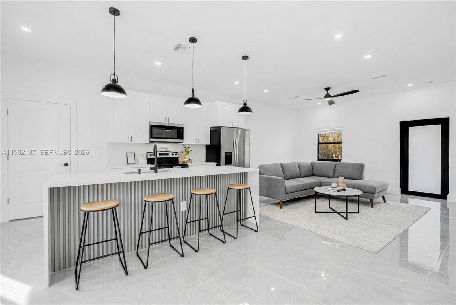 747 Roma Avenue South Lehigh Acres, FL 33974 - Photo 6 of 31 a living room with furniture a flat screen tv and kitchen view