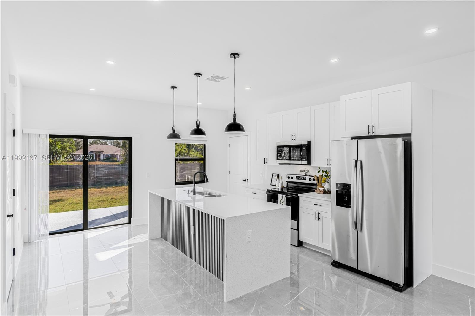 747 Roma Avenue South Lehigh Acres, FL 33974 - Photo 10 of 31 a kitchen with stainless steel appliances kitchen island granite countertop a refrigerator and a sink