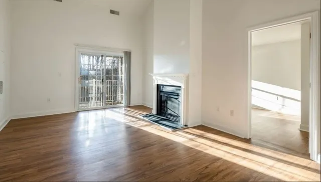 an empty room with wooden floor fireplace and windows