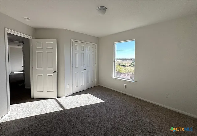 a view of an empty room with window and closet area
