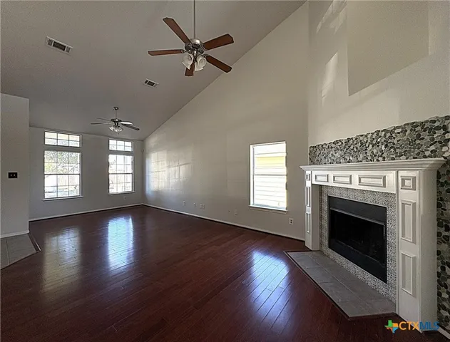 a view of an empty room with wooden floor fireplace and a window