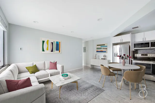 a living room with furniture a flat screen tv and kitchen view