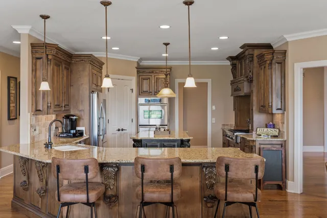 a kitchen with kitchen island a stove a sink a counter space wooden floor and stainless steel appliances